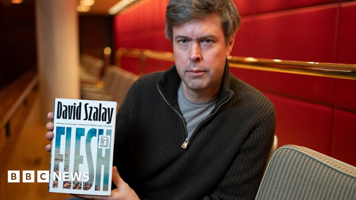 David Szalay holding up the cover of his novel Flesh
