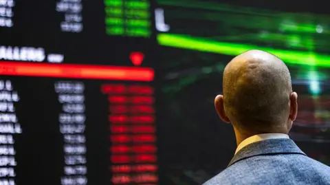 Getty Images A trader on a trading floor looking at stock prices rising and falling
