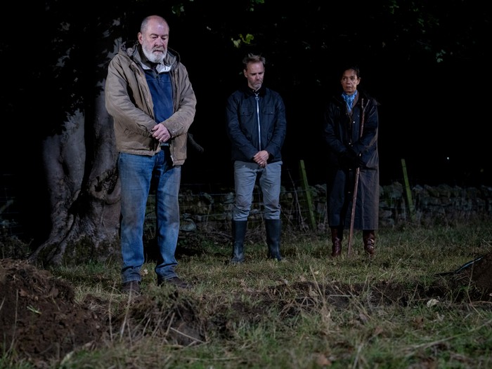 Ray and Celia stand on emotionless as Bear makes a speech by Anya's grave in Emmerdale