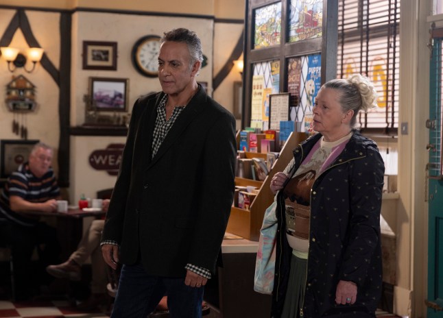 Dev and Bernie stand in the cafe looking concerned in Corrie
