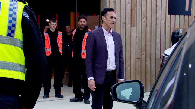 Dylan and Billy watch as Jai is approached by some police cars while outside the depot in Emmerdale