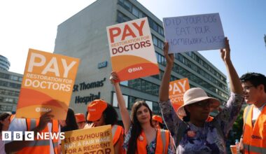 Doctors on strike, holding up placards calling for more pay, one reads: "did your dog eat your homework, Wes?" in reference to Health Secretary Wes Streeting