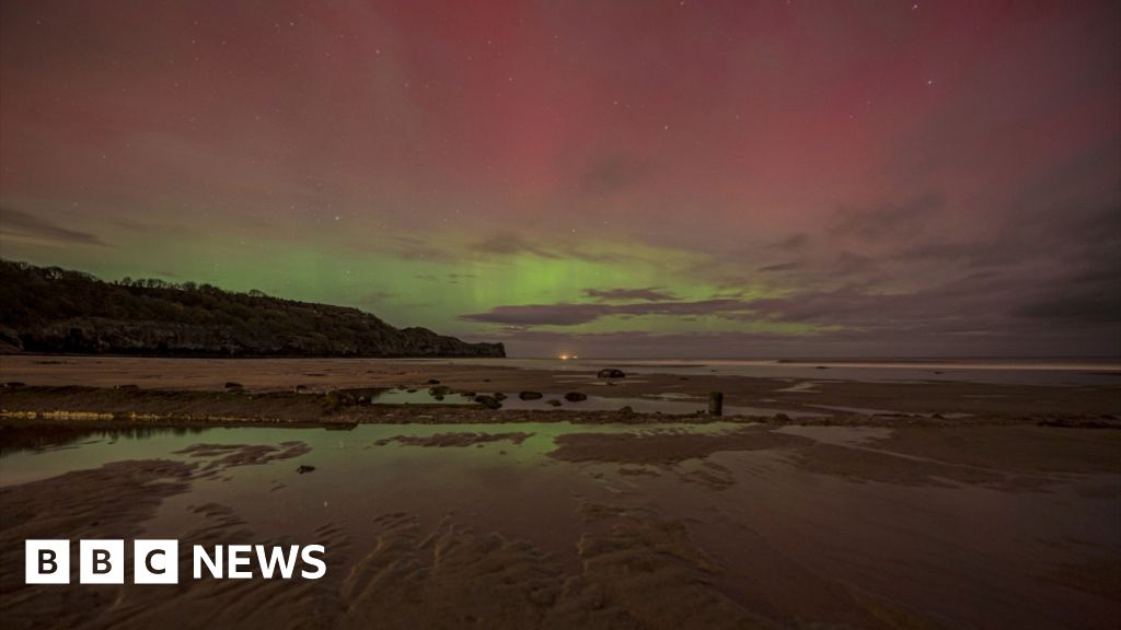 Red and green Northern Lights display above a dark beach