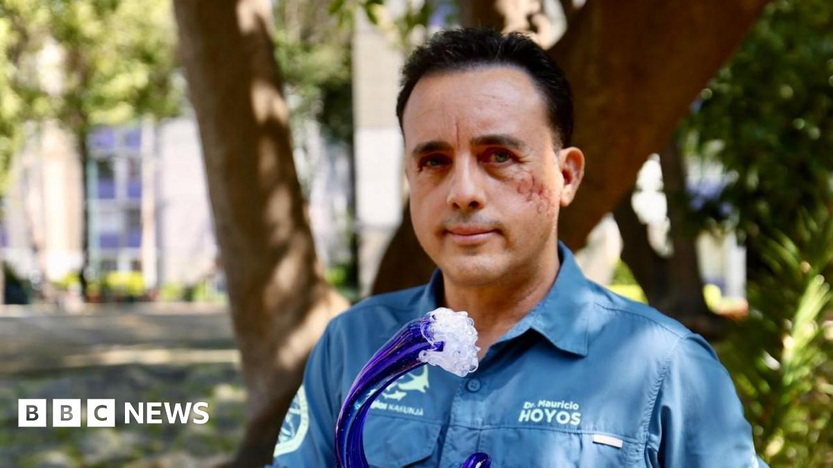 Mauricio Hoyos looks at the camera, while holding a wave-shaped award