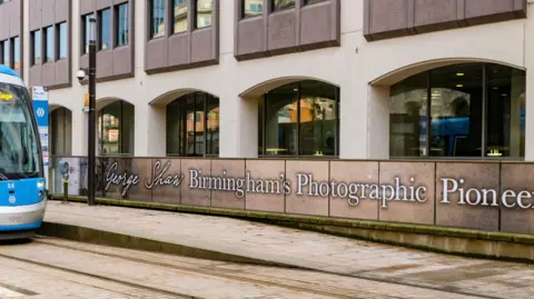 Stacey Barnfield A West Midlands Metro tram is pictures to the left of a long board reading "George Shaw, Birmingham's Photographic Pioneer"