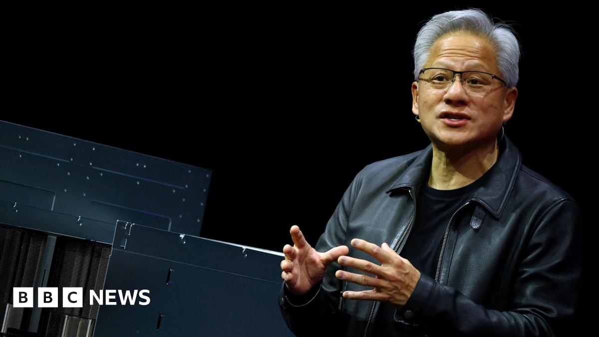 A man wearing a leather jacket speaks with his hands raised. A logo reading "Nvidia" is seen in the background.