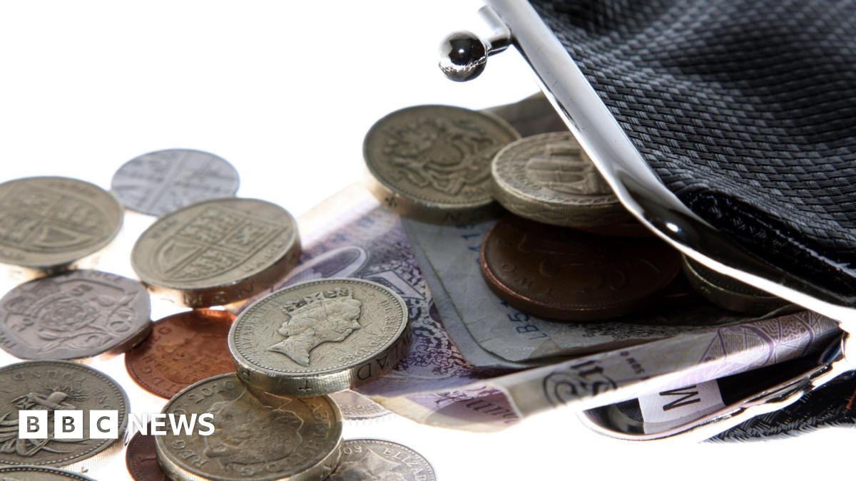 A black purse with the clasp open and money spilling out.