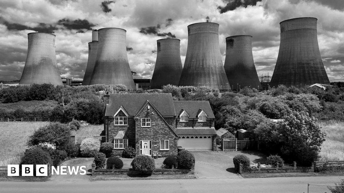 A house in front of Ratcliffe-on-Soar power station's cooling towers in black and white.