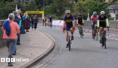 A number of cyclists crossing the finish line in Peebles on the Tour O The Borders - some spectators are lining the route