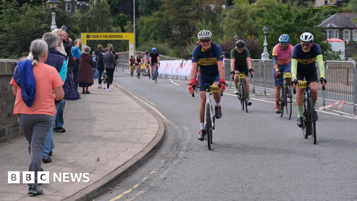 A number of cyclists crossing the finish line in Peebles on the Tour O The Borders - some spectators are lining the route