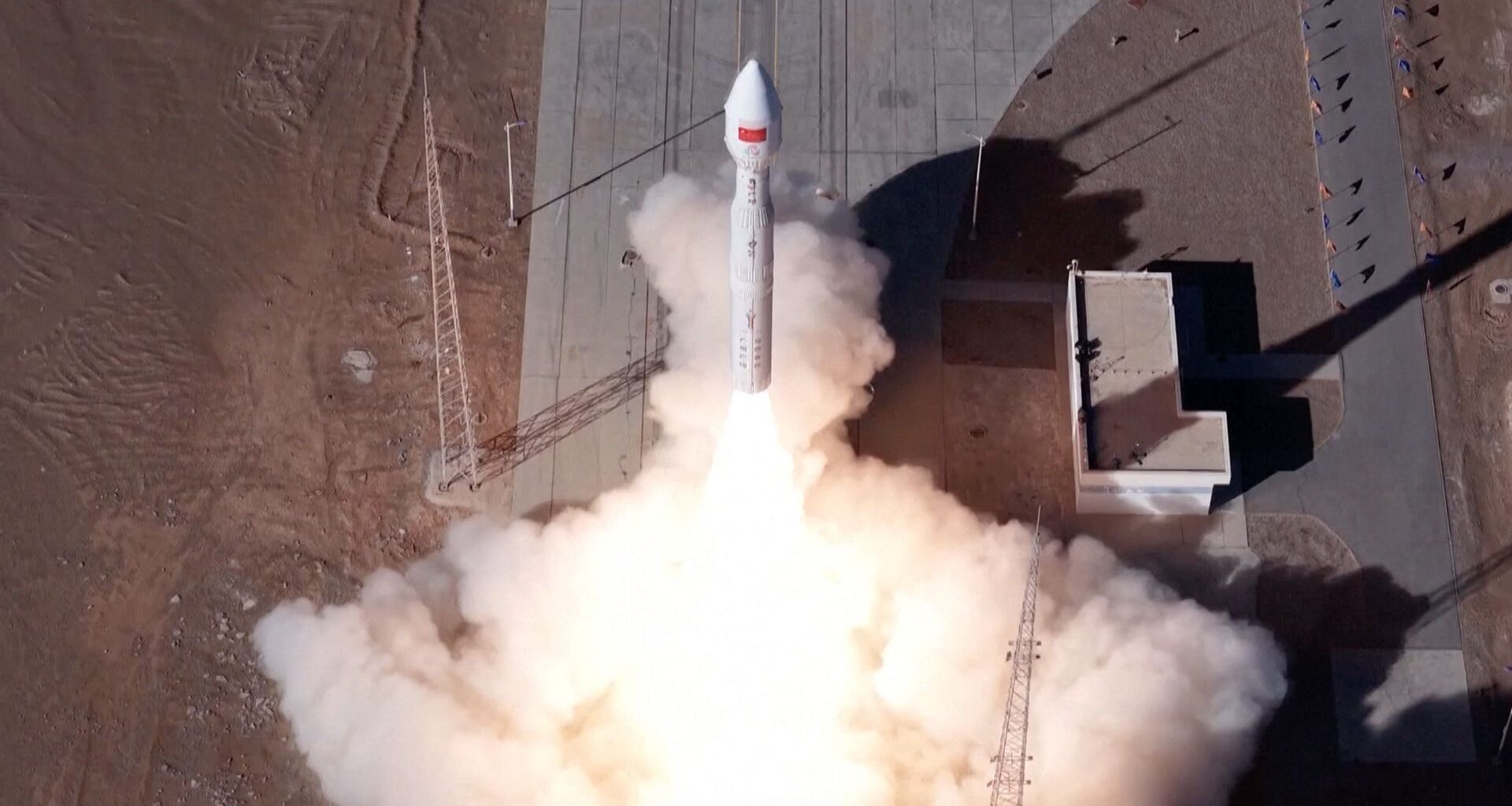 overhead view of a white rocket launching, with a plume of white smoke billowing out from under it