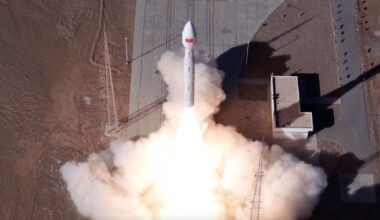 overhead view of a white rocket launching, with a plume of white smoke billowing out from under it