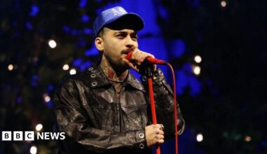 Zayn Malik singing into a red microphone while performing at O2 Academy Leeds