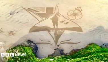Overhead photo showing sand art of a Vulcan aircraft with a poppy, a soldier and union lags
