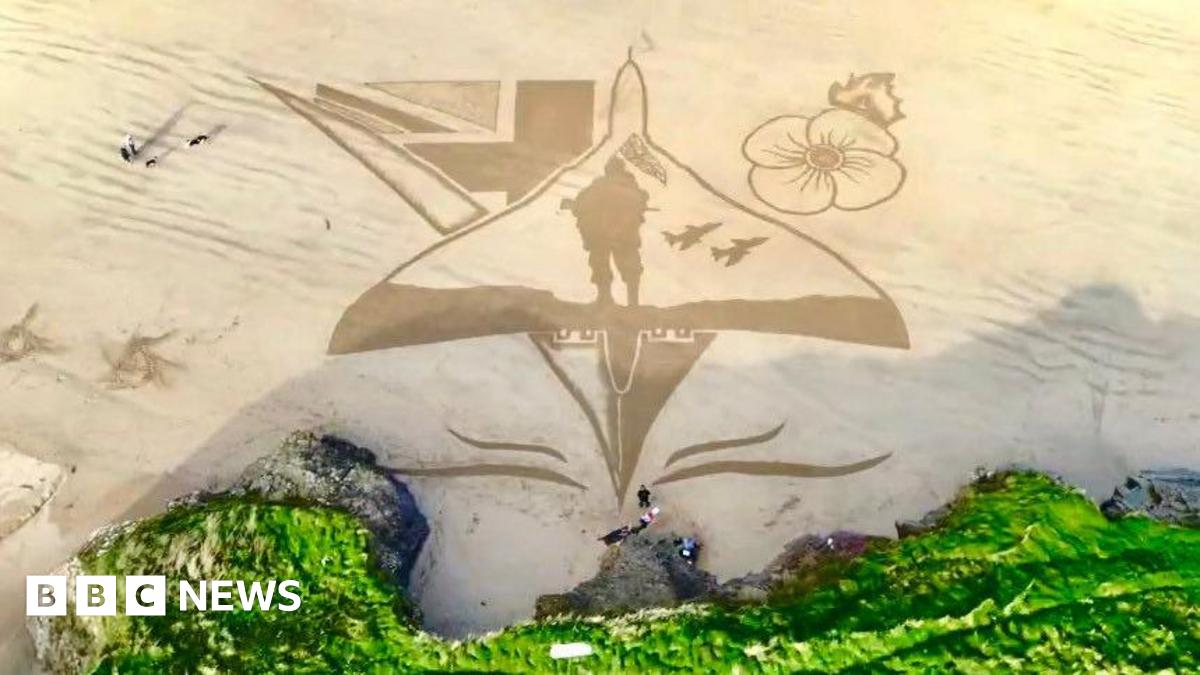 Overhead photo showing sand art of a Vulcan aircraft with a poppy, a soldier and union lags