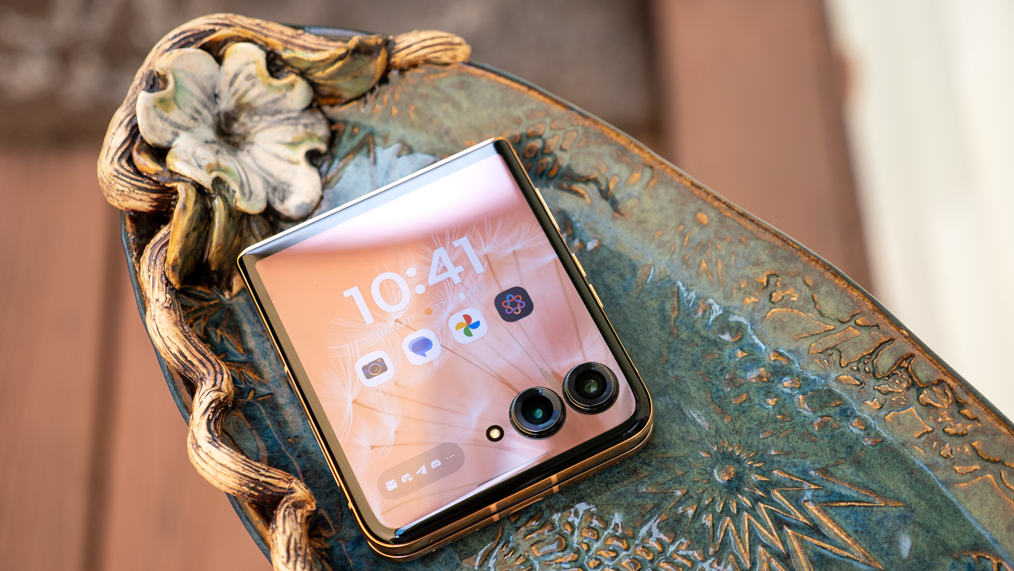 The Motorola Razr Plus 2025 on a fancy plate with its cover screen illuminated and unlocked