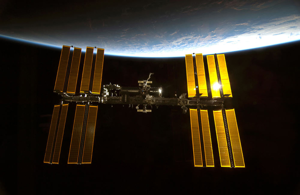 A space station with various solar panels floats above Earth