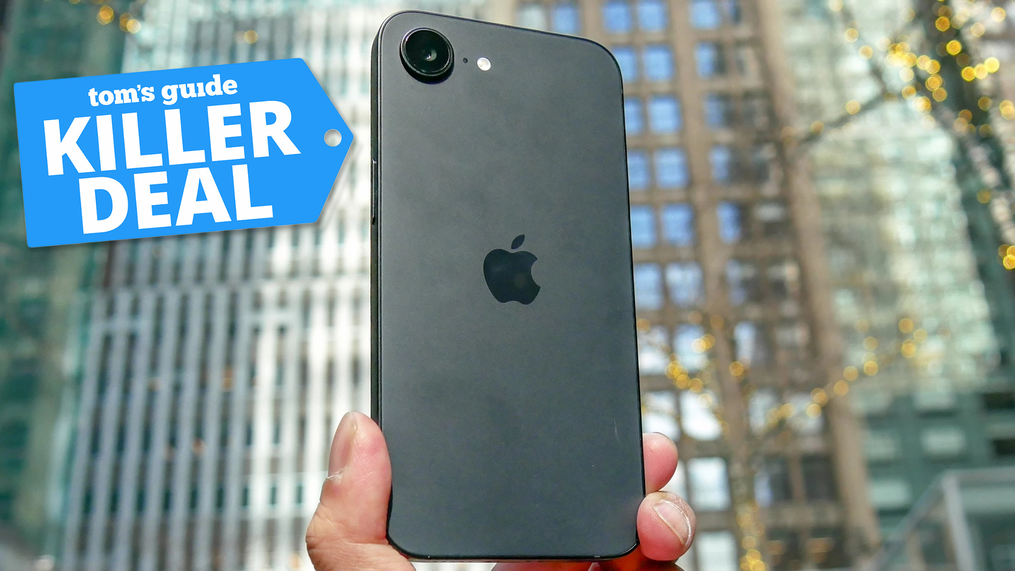 iPhone 16e held in the hand with killer deal badge nearby.