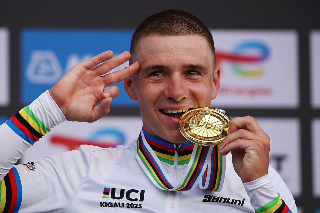 Gold medallist Belgian rider Remco Evenepoel bites on his medal on the podium following the men's Elite Individual Time Trial cycling event during the UCI 2025 Road World Championships, in Kigali, on September 21, 2025. (Photo by Anne-Christine POUJOULAT / AFP)