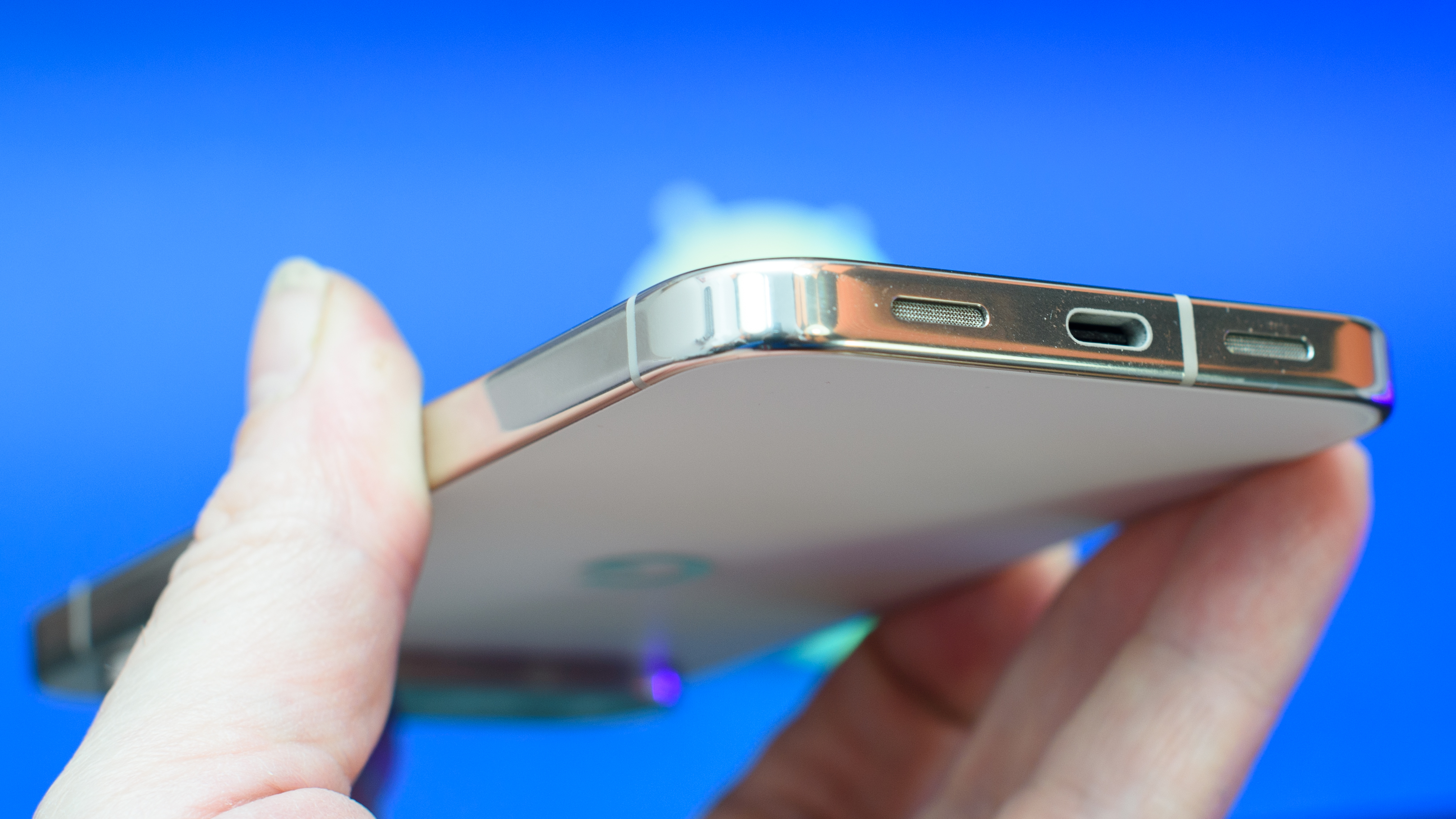 Google Pixel 10 Pro XL in Porcelain against a blue background with a green neon Android figurine in the background