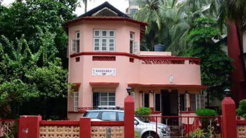 Art Deco Mumbai Trust The pink facade of the Saudades art deco-style family bungalow, built in 1936 in Mumbai's Bandra suburb, features local elements like lattice balcony screens.