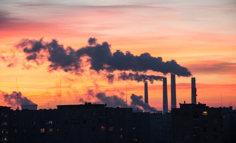 Power Plant emissions seen above residential blocks from a city during sunrise