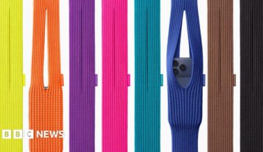 A display of eight brightly coloured knitted iPhone Pocket bags, two with iPhones in them, coloured from the left yellow, orange, purple, pink, turquoise, blue, brown and black.