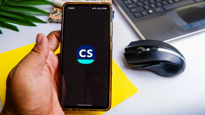 Man holding a phone showing the CamScanner logo on the display