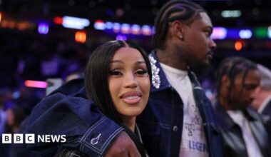 NFL Player Stefon Diggs wraps his arm around his girlfriend, rapper Cardi B, at a basketball game.
