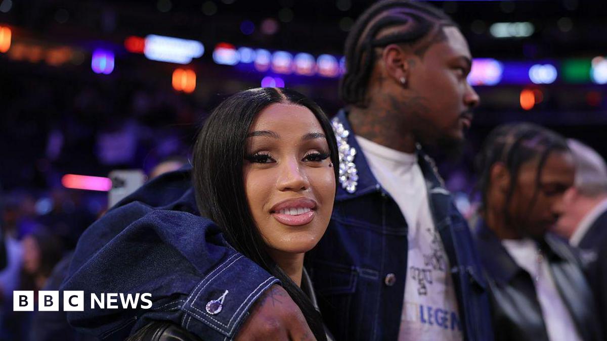 NFL Player Stefon Diggs wraps his arm around his girlfriend, rapper Cardi B, at a basketball game.