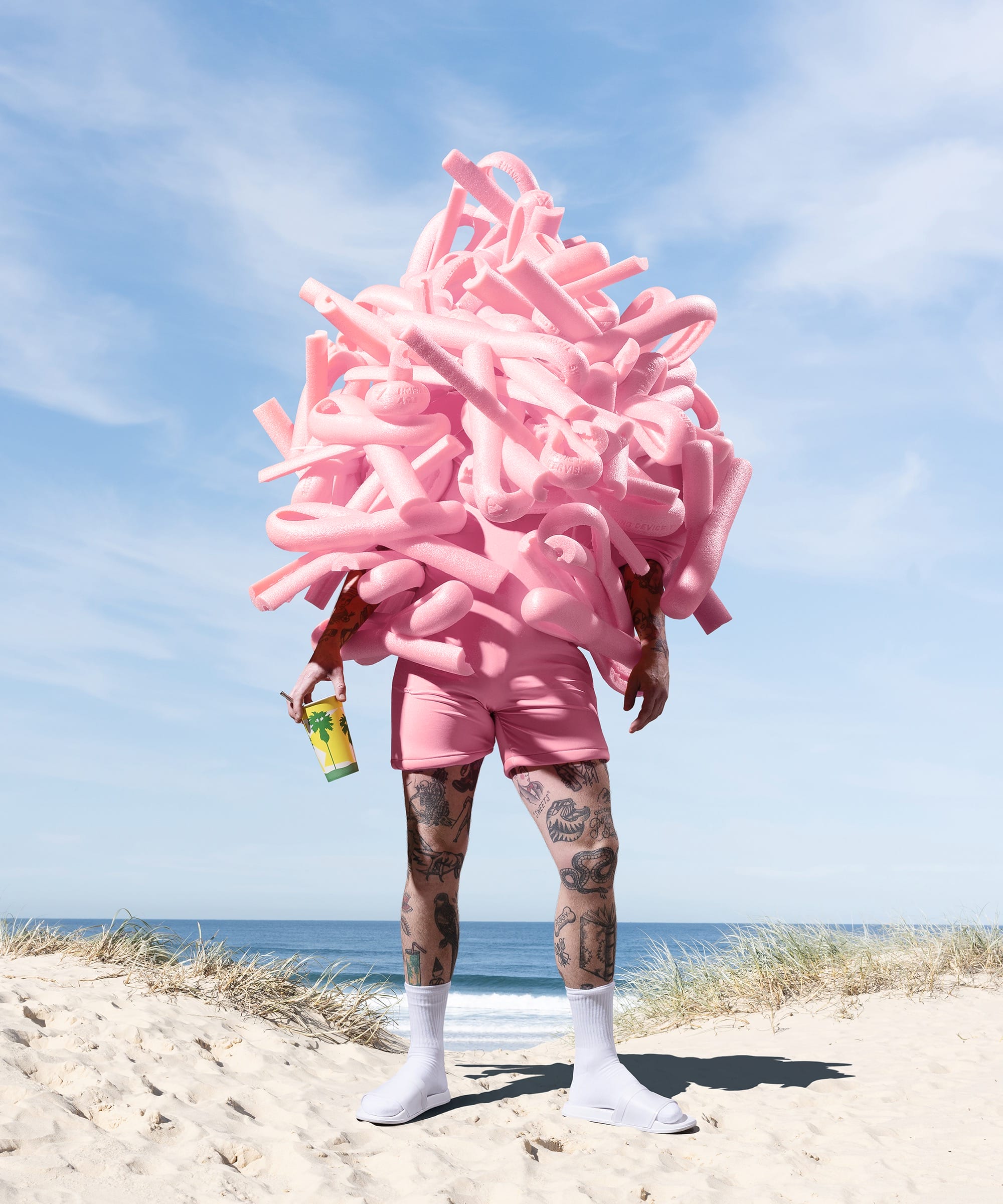 a photograph by Gerwyn Davies of a brightly colored abstract costume obscuring the top half of his body in a seaside landscape