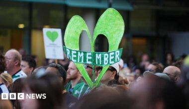 A crane is seen over the Grenfell Tower in west London where a large green heart is still visible on the top floors of the tower block