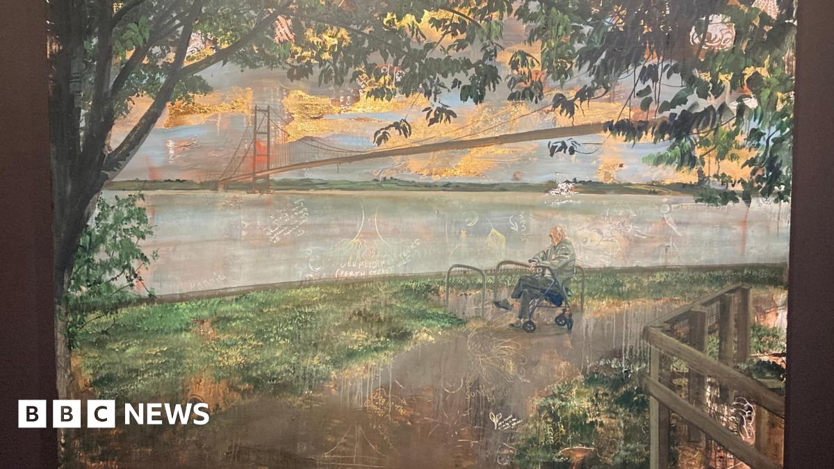 A photo of a painting hanging in a gallery, the paining portrays a man sat resting on a walking aid looking out towards the River Humber, with the Humber Bridge behind him. A tree frames the scene.