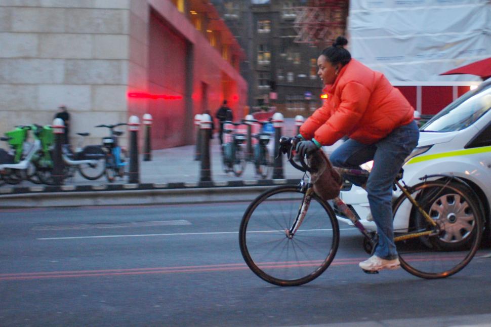 Female cyclist in London wearing a red coat on a steel road bike 
