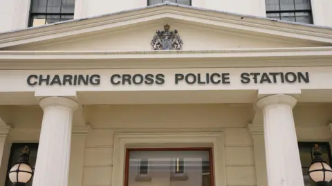 PA Media Black Charing Cross police station sign below a coat  of arms and two white pillars and lights
