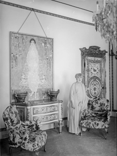 Black and white photo of a woman stood next to a life-size portrait