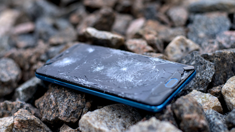 closeup of smartphone on ground with a cracked screen.