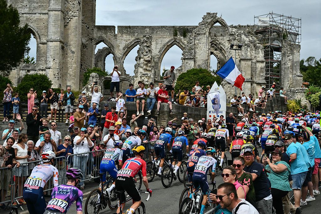The pack of riders (peloton) cycles past the ruins of the church of Ablain-Saint-Nazaire during the 1st stage of the 112th edition of the Tour de France cycling race, 184.9 km starting and finishing in Lille Metropole, northern France, on July 5, 2025. (Photo by Marco BERTORELLO / AFP)