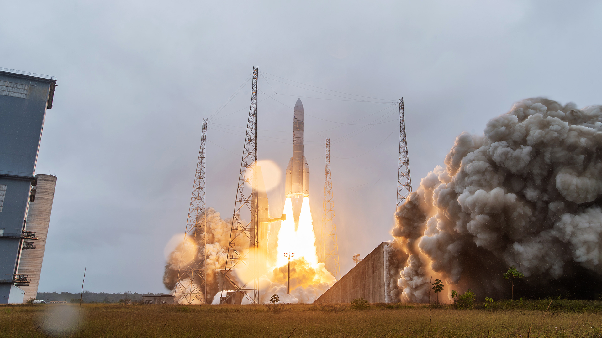 a white rocket launches into a cloudy daytime sky