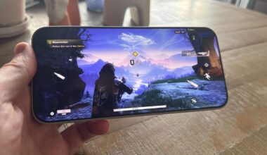 A hand holding a phone that's playing a third-person shooter game.