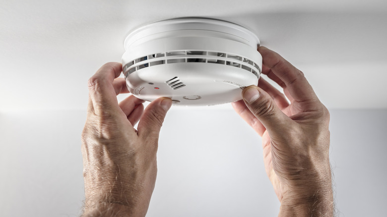 A smoke detector being installed on the ceiling