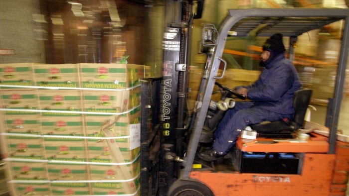 Larry Harris drives a forklift carrying boxes of bananas from Ecuador at the Los Angeles Regional Food Bank.