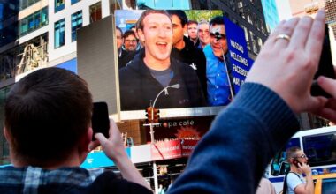 Mark Zuckerberg appears on a large screen in Times Square, smiling, as people take photos during Facebook’s IPO launch in 2012