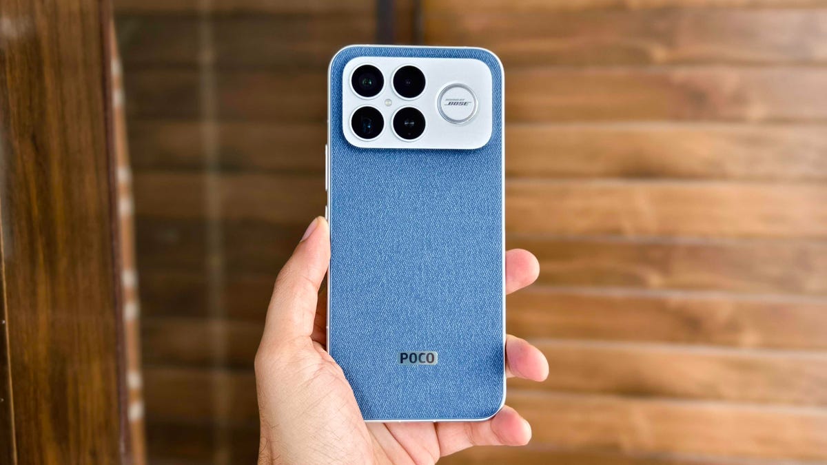 Hand holding the Poco F8 Ultra with denim back and 4 cameras.