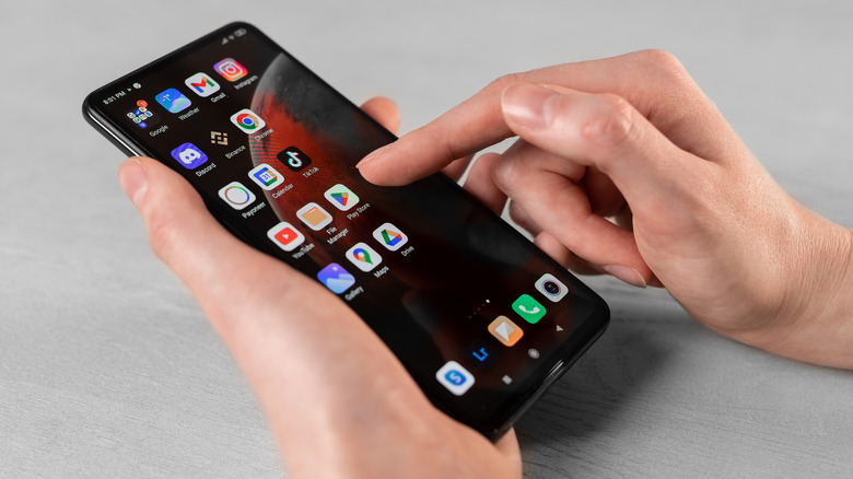 Person holding Android smartphone with apps showing on screen