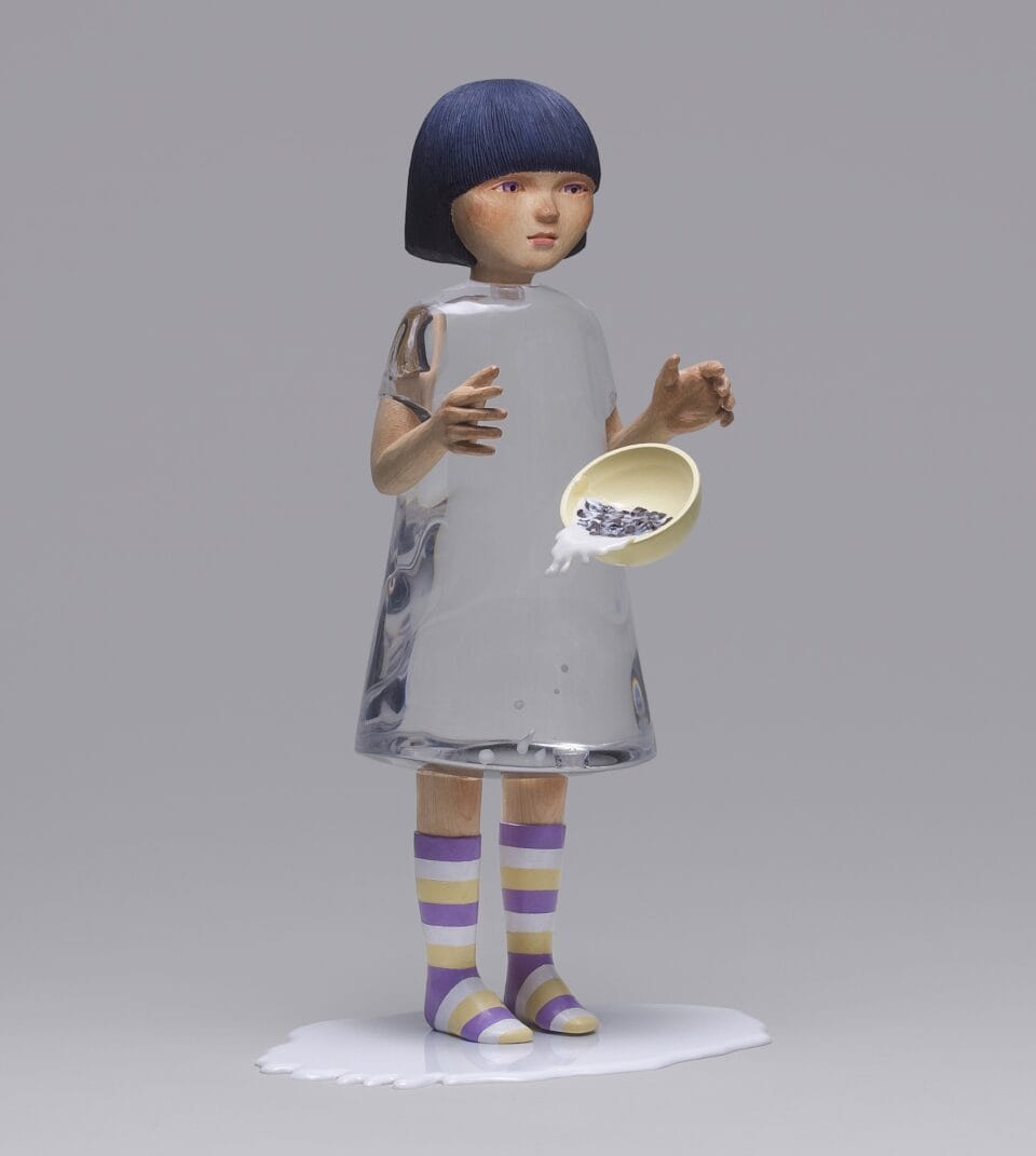 a small sculpture by Ayako Kita made of cypress and acrylic resin, depicting a young woman or girl with a clear dress, dropping a bowl of cereal