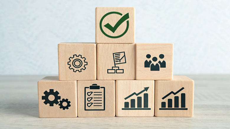 Wooden blocks with work icons arranged in the shape of a pyramid on a desk