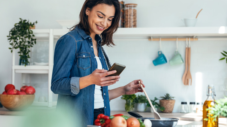 woman cooking using a recipe on her phone