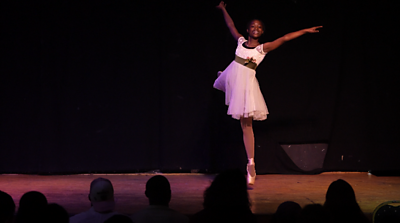 Photo of a ballerina performing onstage in front of an audience. 