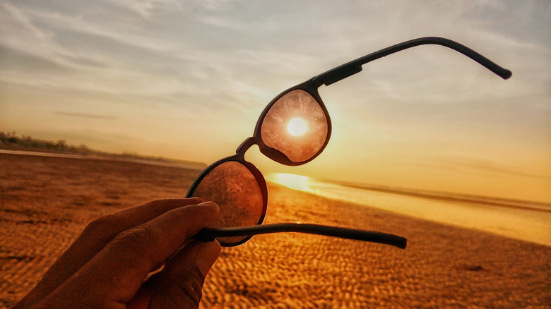Holding a pair of sunglasses up to the sun
